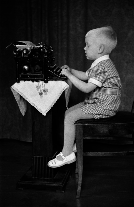 Lapsi "kirjoittaa" kirjoituskoneella. Kuva: Väinö Kannisto, Helsingin kaupunginmuseo.