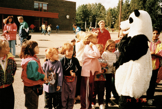Panda-karhu ja lapsia Rintinpolun koulun pihalla Kontulassa. Helsinki, 1996. Kuva: Pentti Huttunen. Helsingin kaupunginmuseo. CC BY 4.0.