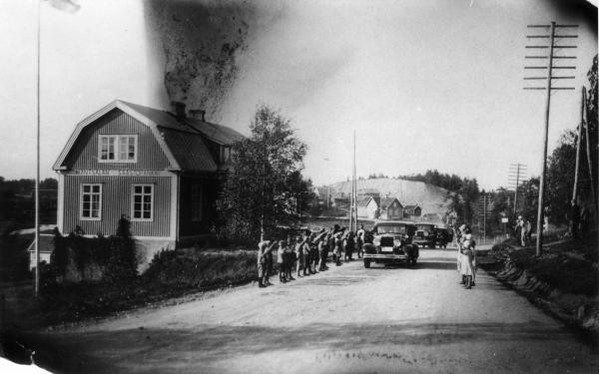 Lapsia tervehtimässä autokolonnaa Mäntsälän Säästöpankin kohdalla kirkonmäellä. Ilmeisesti 1930-luvun loppu. 1935–1949. Kuva: Museovirasto. CC BY-NC-ND 4.0.