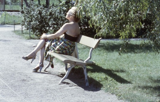 Nainen puistonpenkillä ottamassa aurinkoa. Helsinki, 1950. Kuva: Rune Uggla. Helsingin kaupunginmuseo. CC BY 4.0.