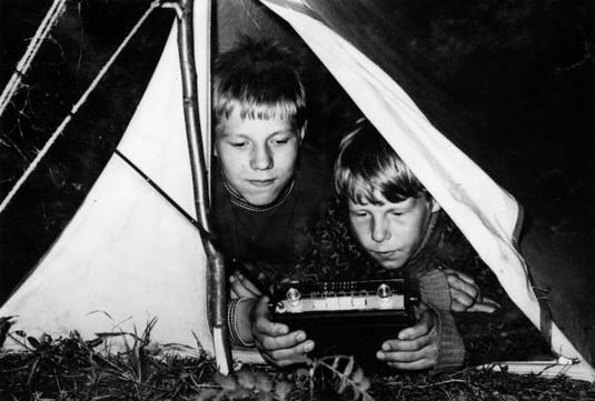 Olli ja Seppo Packalén kuuntelemassa Hitachi-merkkistä matkaradiota Vantaanjoen varressa (n. 1965). Kuva: Pentti Leinonen. Nurmijärven museo. CC BY-NC-ND 4.0.