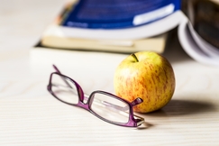 Omena ja silmälasit opiskelijan pöydällä. Kuva: Kuva-Plugi.
