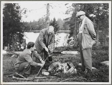 Miehet nuotion ääressä. Äänitysmatka Sotkamon, Kuhmon, Suomussalmen ja Kuusamon pitäjiin. Keskellä Lauri Hakulinen. 1951. Kuva: Jouko Hautala. Museovirasto.