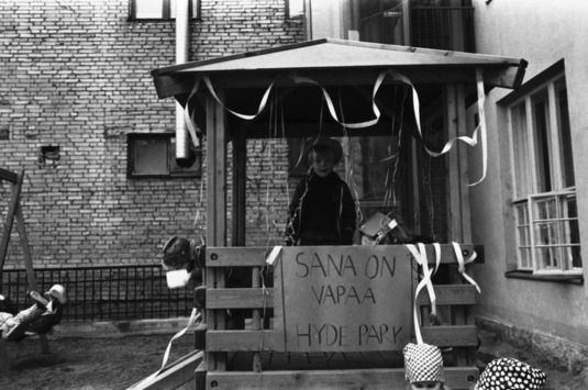 Poika seisomassa serpentiinein koristellussa katoksessa. Vironniemen päiväkoti. 30.4.1982. Kuva: Eeva Rista. Helsingin kaupunginmuseo. CC BY 4.0.