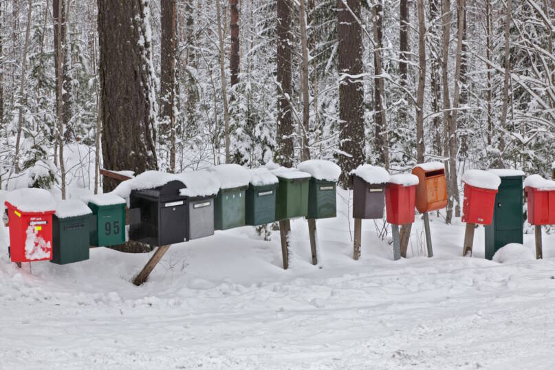 Rivi erilaisia postilaatikoita lumisessa maisemassa, taustalla metsää. Kuva: Anne Saarinen, 2013. Vastavalo.