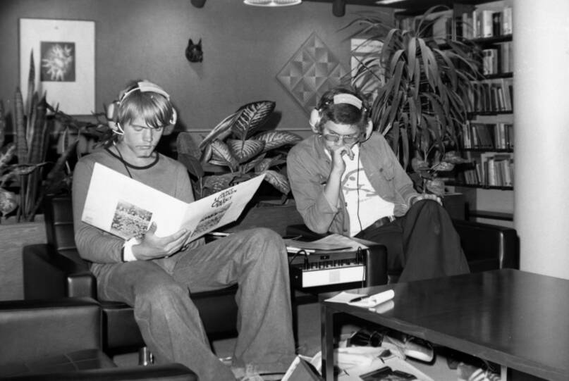 Kaksi nuorta istuu kuuntelemassa kuulokkeilla musiikkia Lahden kaupunginkirjastossa vuonna 1974. Vasemman puoleisen nuoren kädessä on levy Juice Leskinen ja Coltus Int. Kuva: Lahden museot. CC BY 4.0.