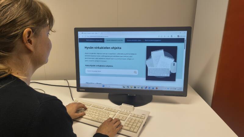 Henkilö tietokoneella, jonka ruudulla auki Hyvän virkakielen ohjeita -verkkosivu.