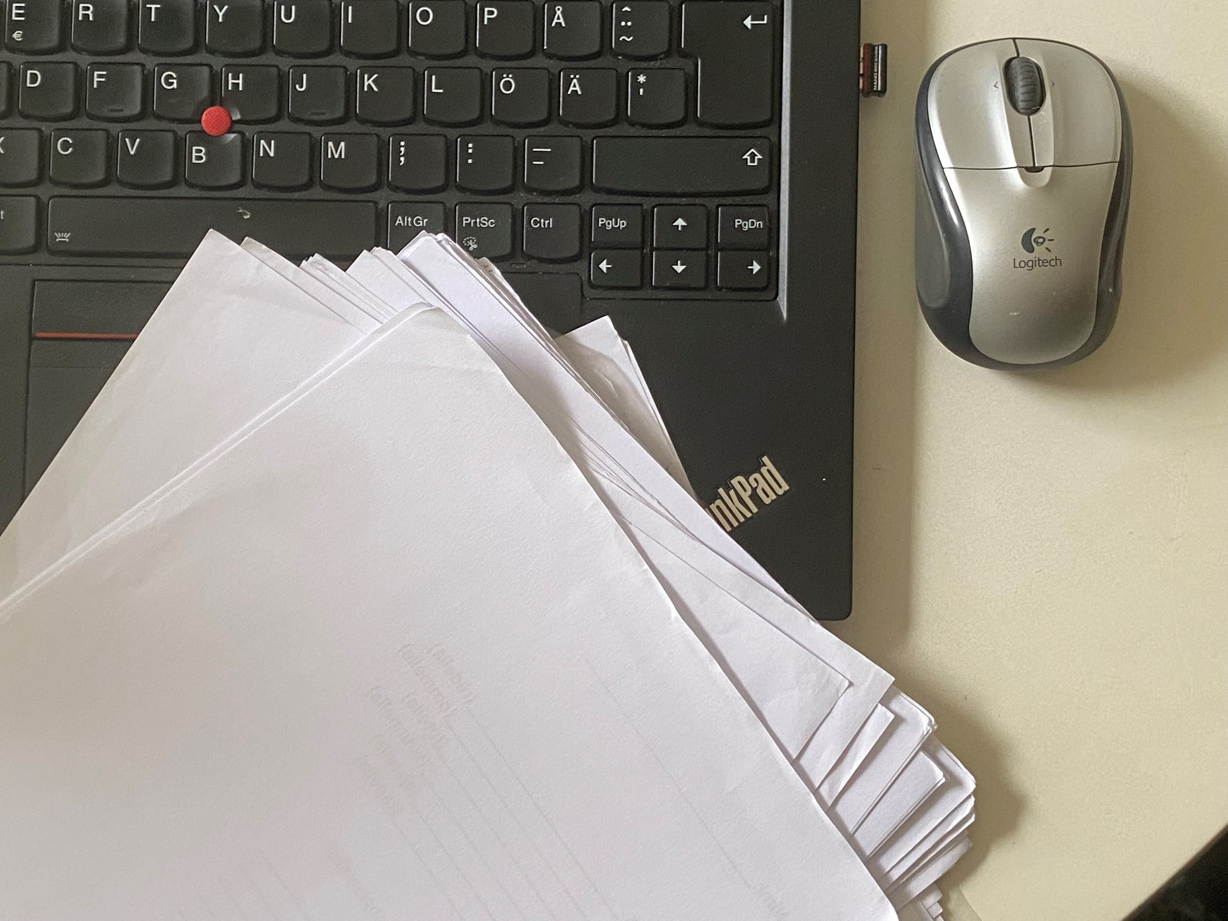 Tietokone, hiiri ja paperinippu. Kuva: Teresa Damski, Kotus.