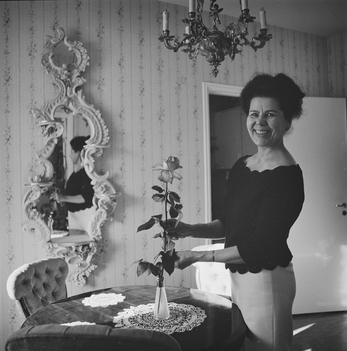 Kirjailija Taru Stenvall asettelemassa ruusua maljakkoon Helsingissä vuonna 1967. Kuva: Pekka Kyytinen. Museovirasto. CC BY 4.0.