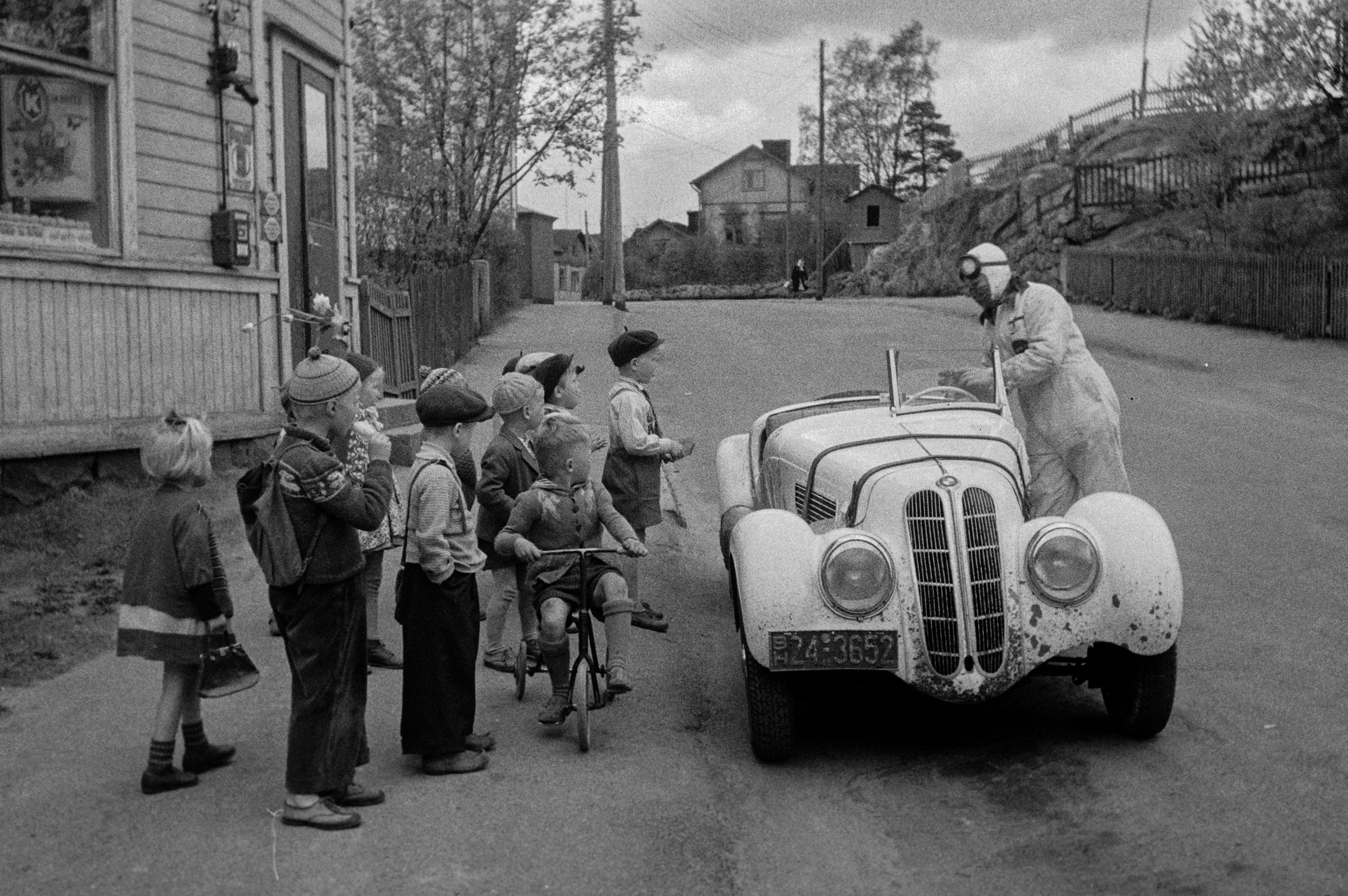 Lapsia, kilpa-ajaja Leo I. Mattila ja BMW-merkkinen kilpa-auto, 1950-luku. Kuva Eino Heinonen. Helsingin kaupunginmuseo. Public domain.