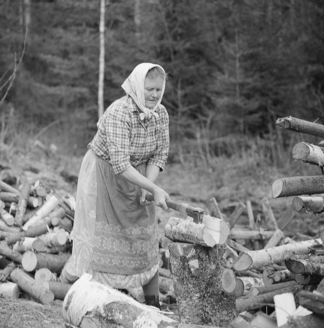 Vanha nainen hakkaa halkoja. Kuva: Kanerva Teuvo, Museovirasto.