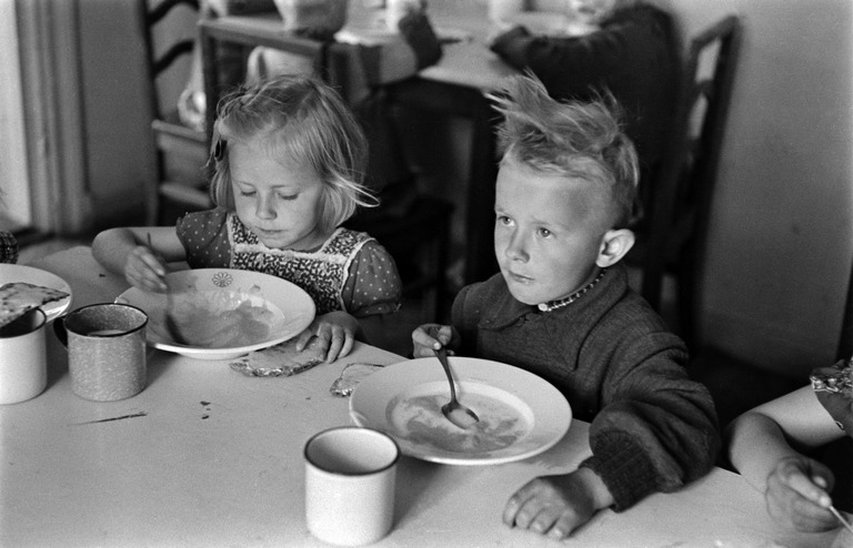 Kaksi lasta syömässä Elannon kesäsiirtolassa Sompasaaressa 1950-luvulla. Kuva: Eino Heinonen. Helsingin kaupunginmuseo.