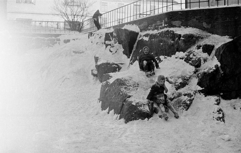 Lapsia laskemassa mäkeä Agricolankujan kallioilla. Helsinki, 1958. Kuva: Väinö Kannisto. Helsingin kaupunginmuseo.