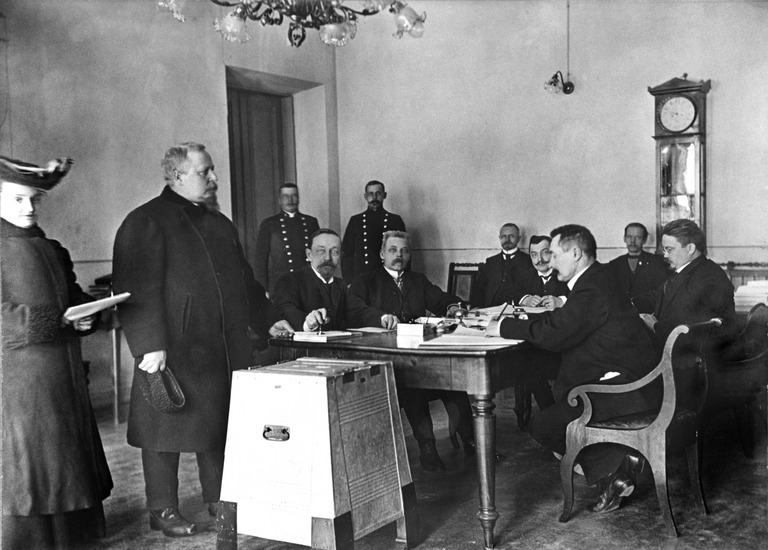Jyväskylän lyseon lehtori pudottamassa äänestyslippunsa vaaliuurnaan. Eduskuntavaalit maaliskuussa 1907. Kuva: Helsingin kaupunginmuseo. CC BY 4.0.