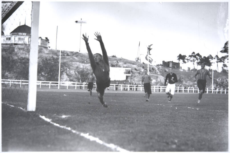 Jalkapallo-ottelu HIFK ja Helsingin Toverit Pallokentällä. Maalivahti syöksyy torjuntaan. Helsinki, elokuu 1934. Kuva: Pietinen. Museovirasto. CC BY 4.0.