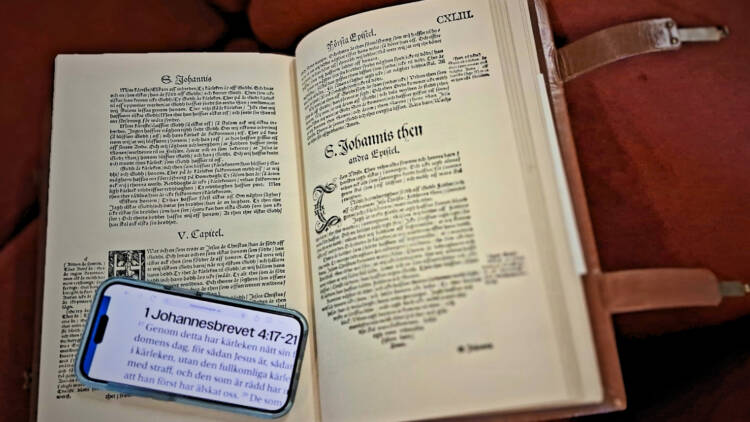 En gammal bibel uppslagen med en mobiltelefon liggande på den gamla texten.