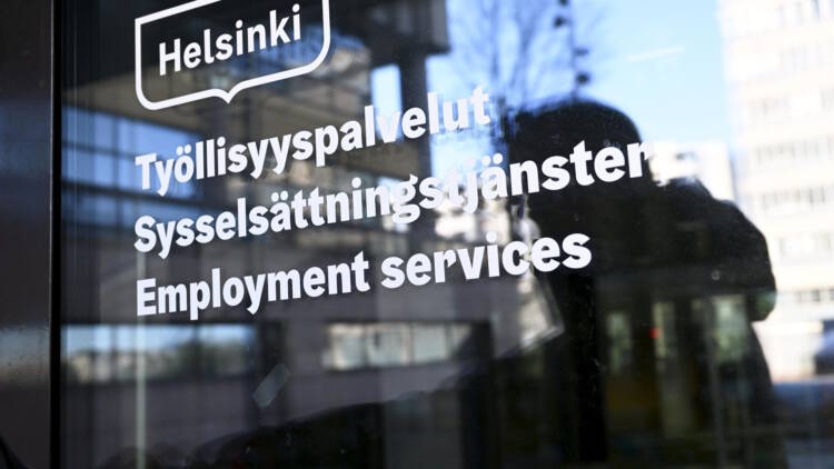 Ihminen avaamassa Pasilan TE-toimiston ovea, jossa on tekstiä kolmella kielellä.