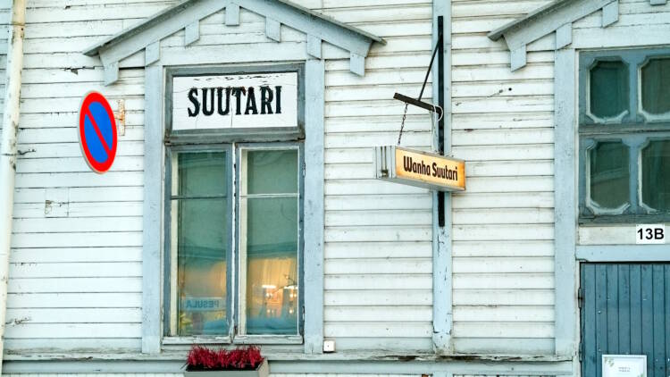 Sininen puutalo, jonka seinässä on kyltit "Suutari" ja "Wanha suutari". Kuva: Yrjö Keränen. Vastavalo.